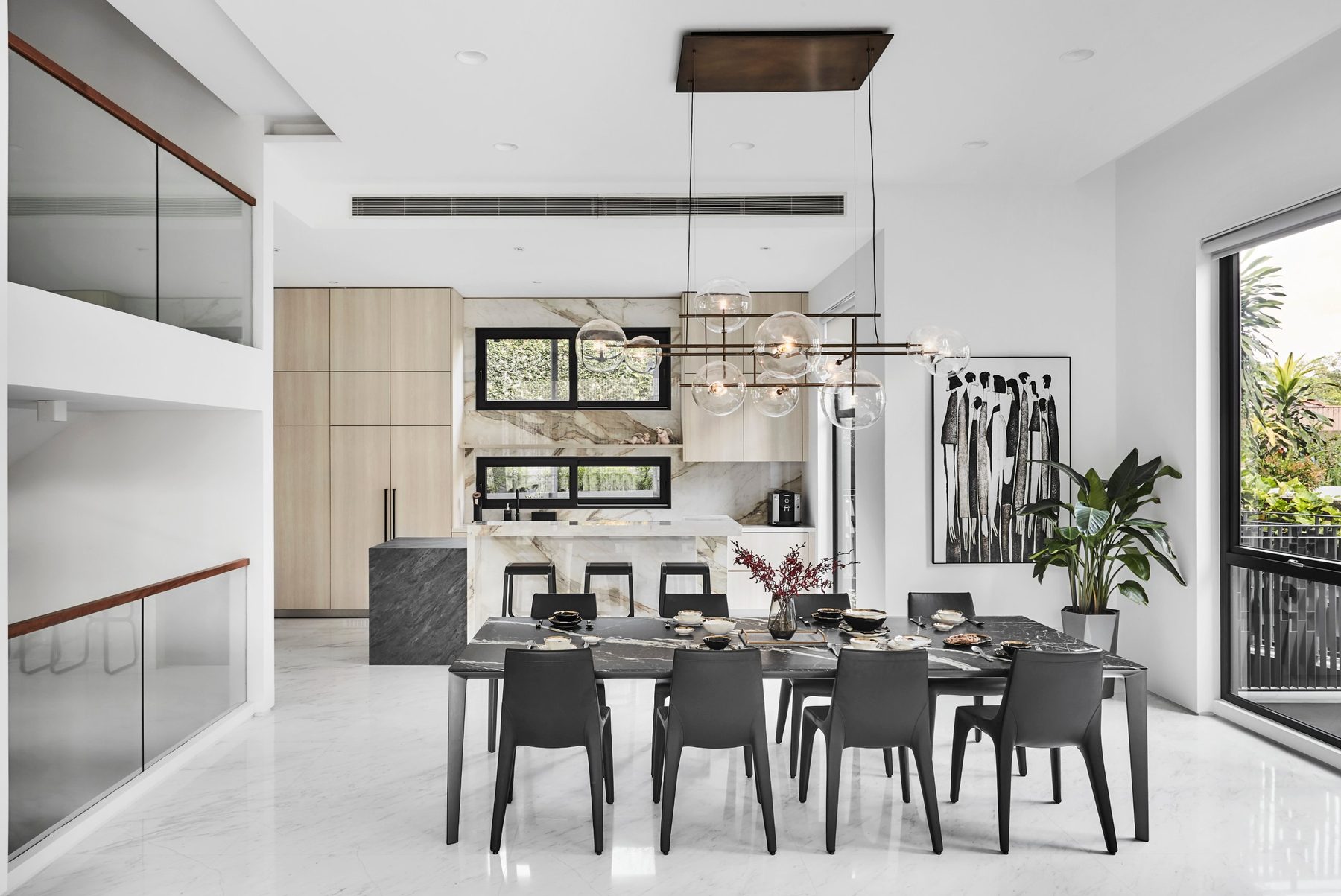 Dining area with a dark-topped table, glass globe pendant light and garden views at the Namly Hill residence.
