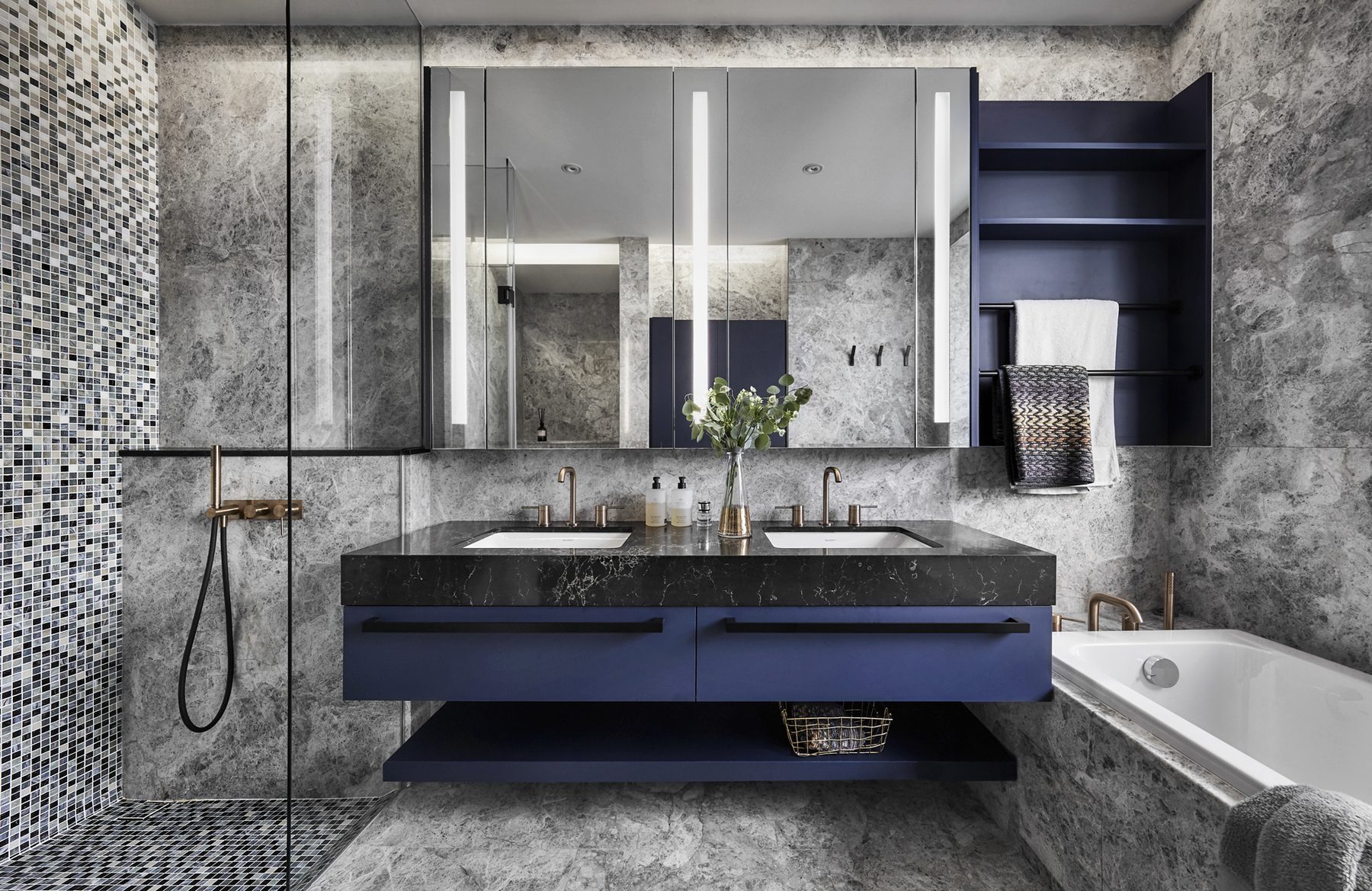 Bathroom with a blue floating vanity, dark stone countertop, brass fittings and grey marble walls, Ardmore Park (2020)