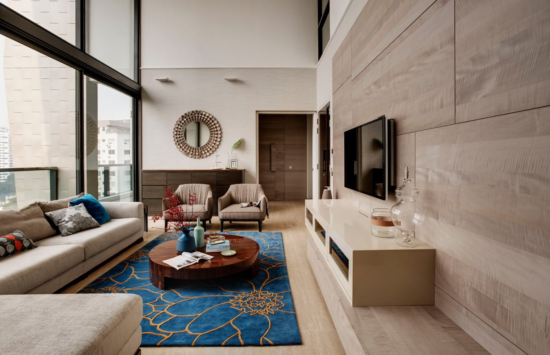 Double-height living room with floor-to-ceiling glazing, a timber-panelled television wall and a blue patterned rug, Thomlison Road (2015)
