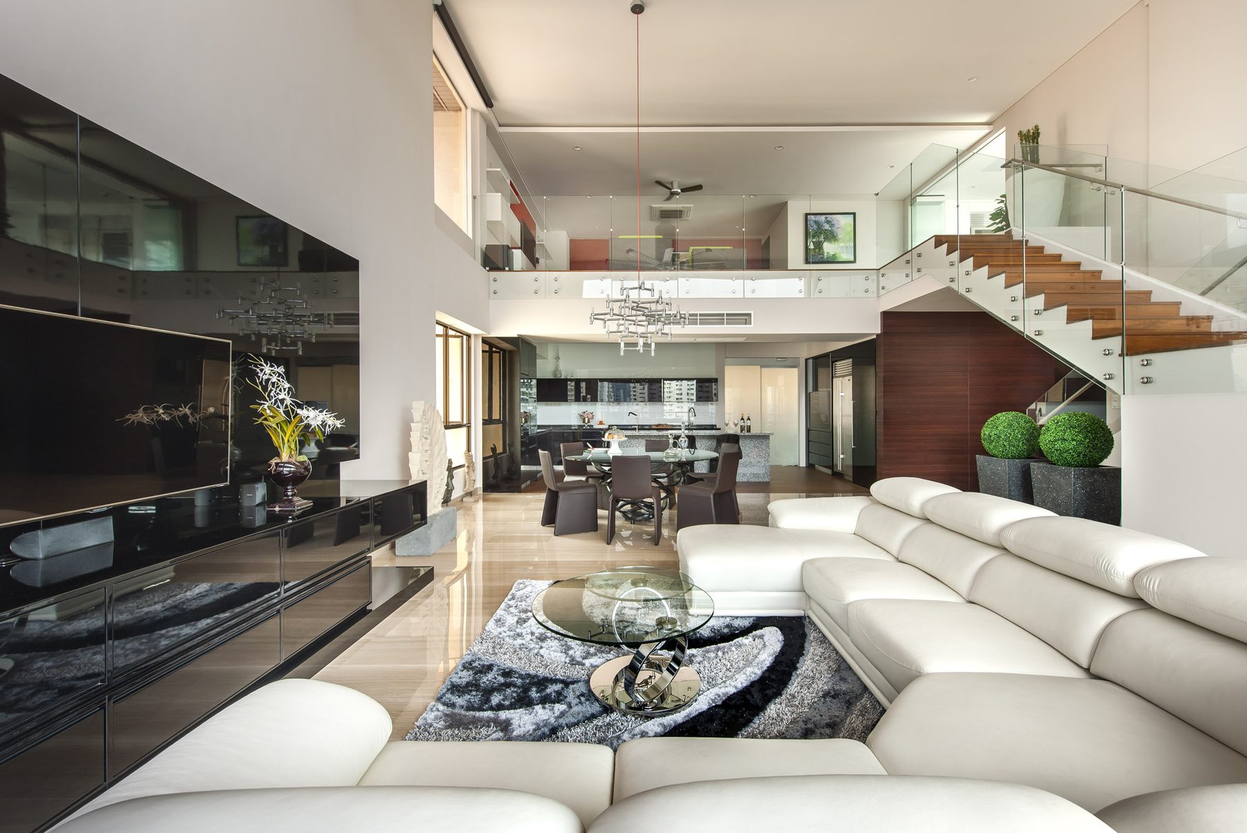 Double-height living and dining area with a white leather sectional, glass-balustraded staircase and mezzanine, Yong An Park (2012)